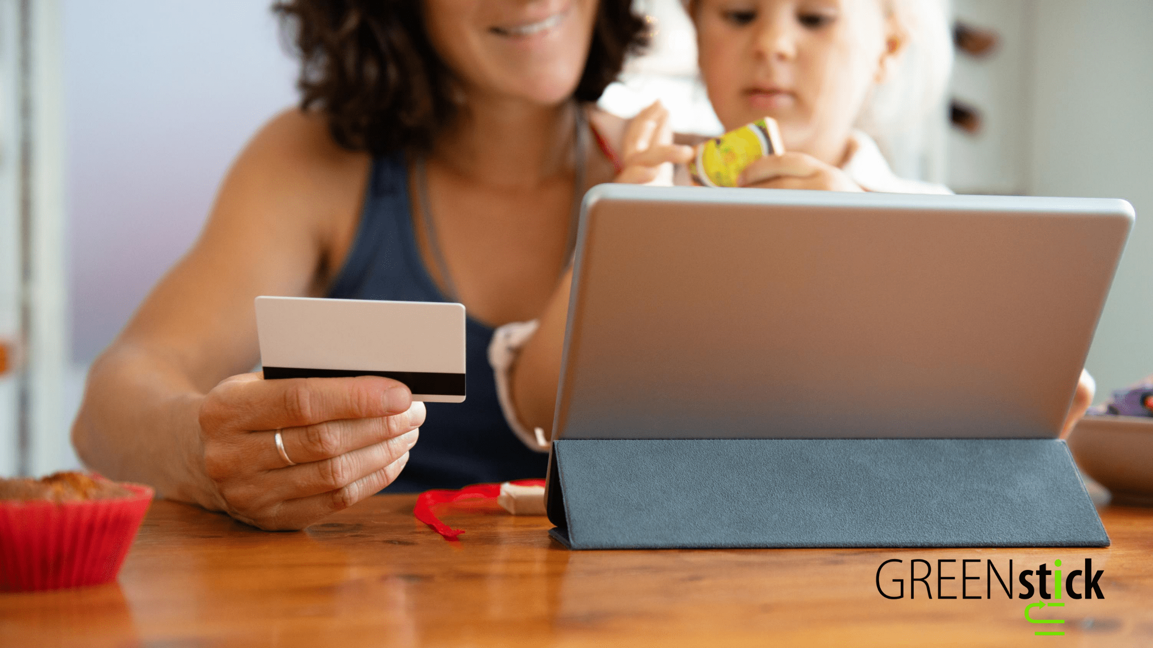 Adult women and baby girl shopping online on an ipad using a business gift card to complete their purchase. 